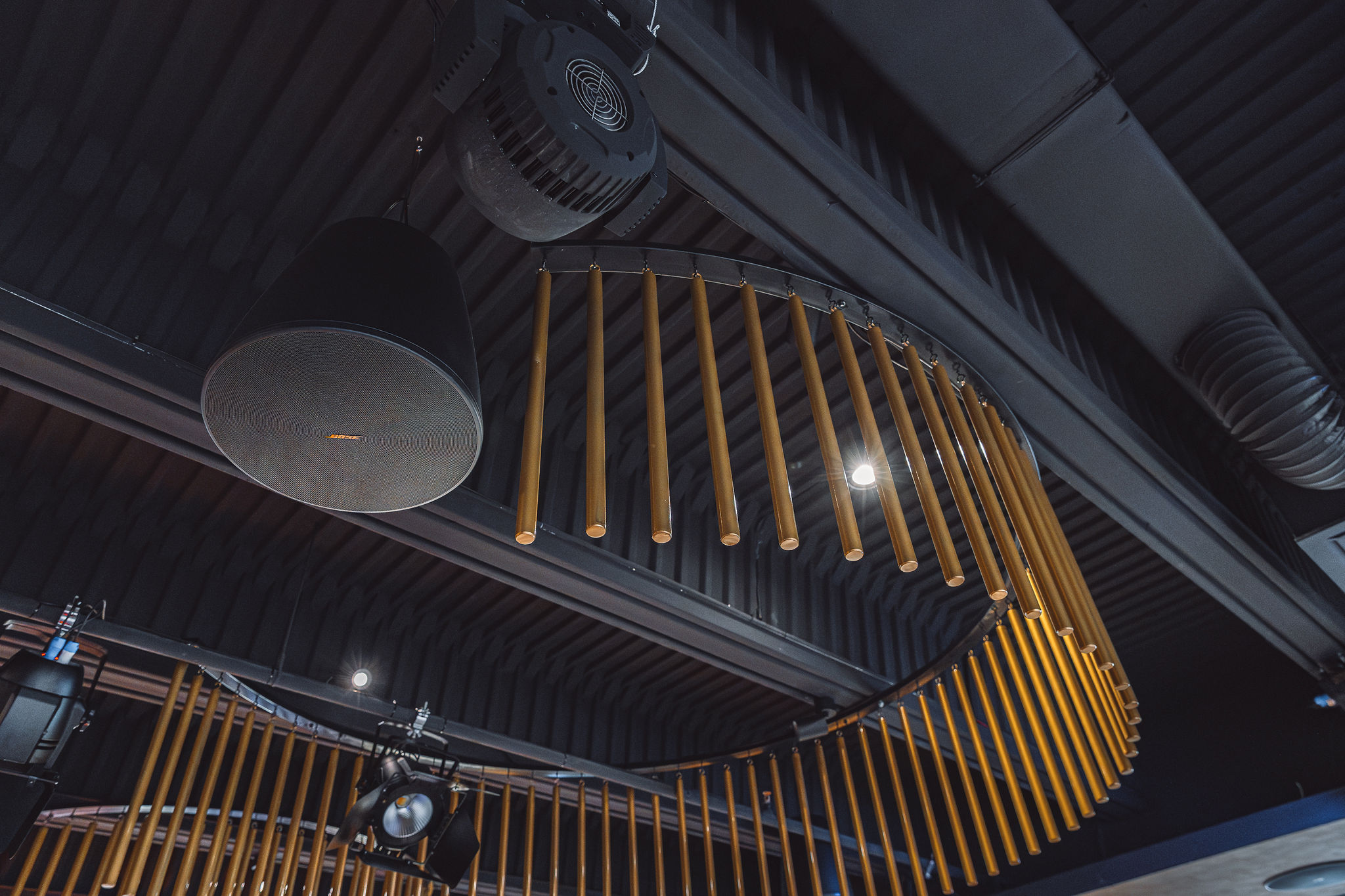 Bose pendant speaker with visible orange Bose logo hanging alongside gold chandeliers at Level Restaurant Split