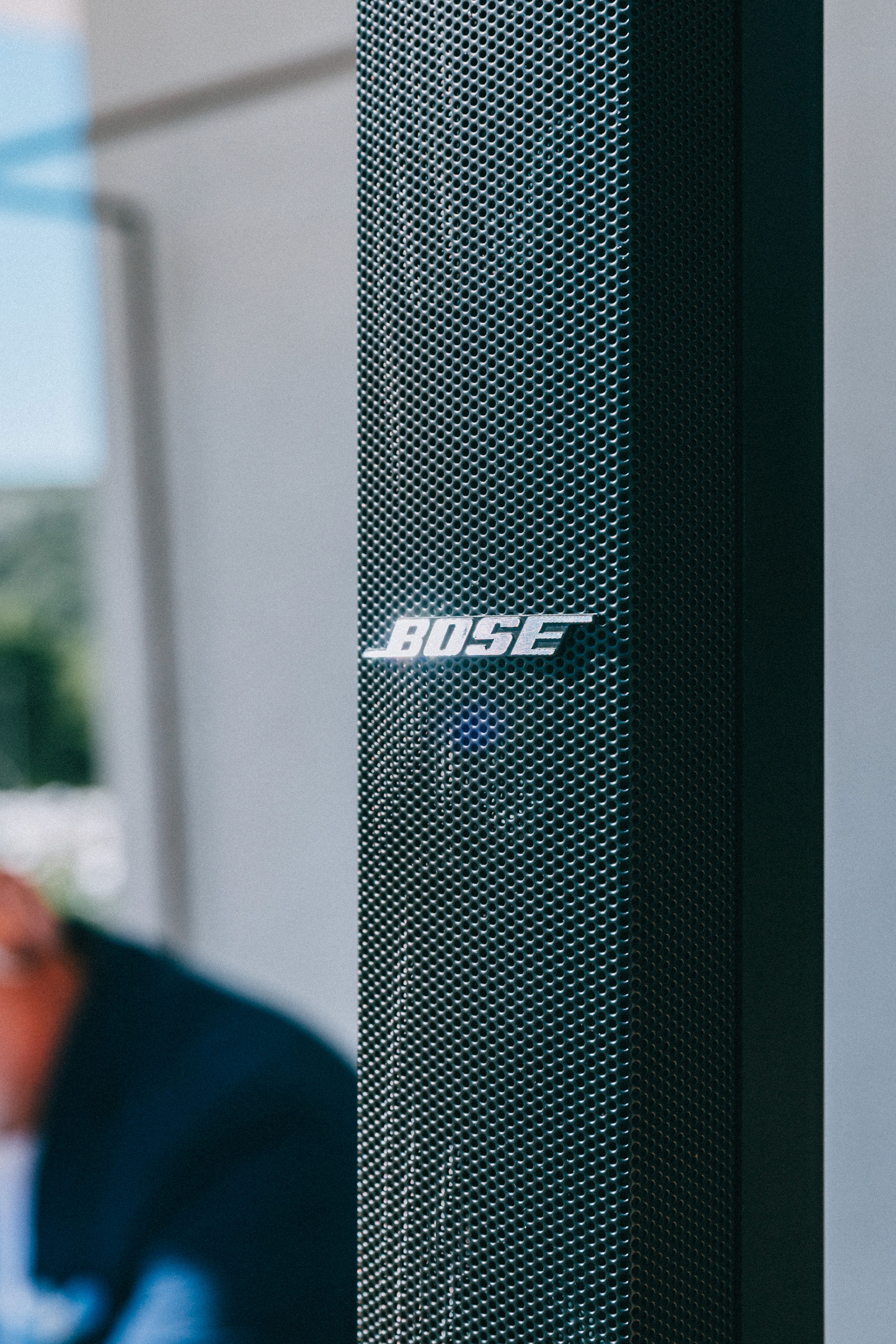 Close-up of Bose column speaker branding with DJ performing in the background at outdoor villa event