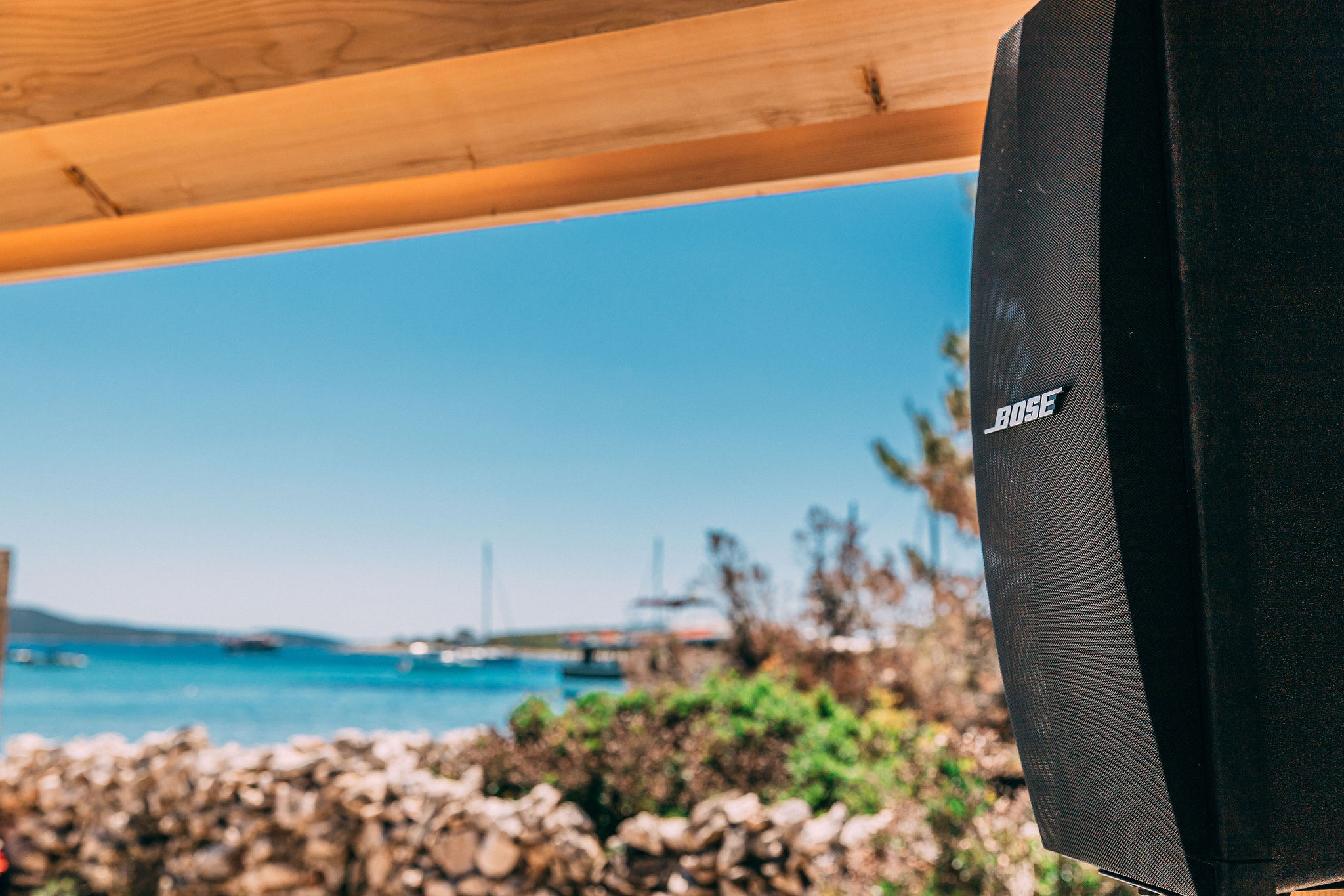 Bose Professional speaker mounted on wooden beam with turquoise Adriatic Sea stretching to horizon behind it