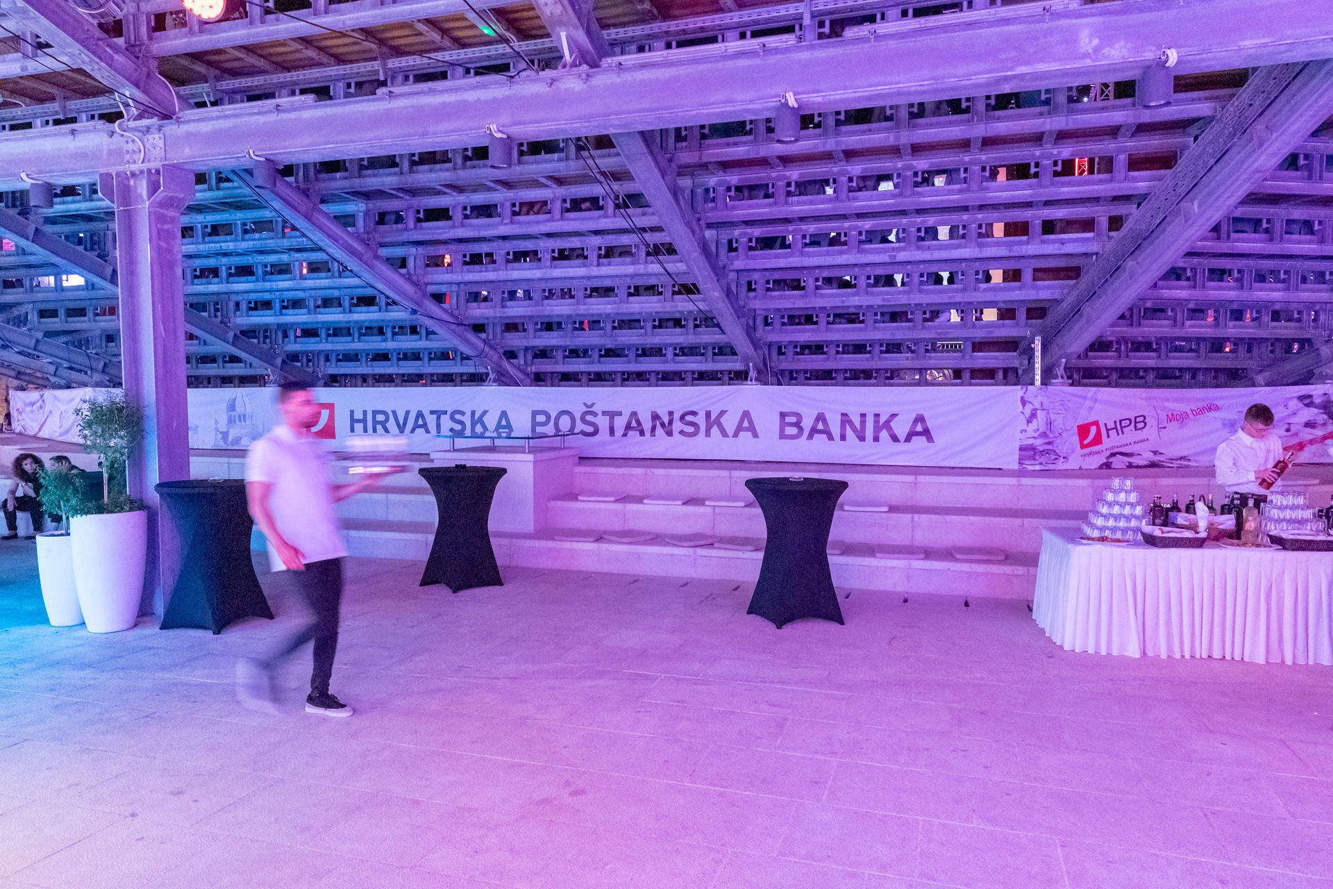 Corporate event fortress venue with purple uplighting, cocktail tables, and branded setup