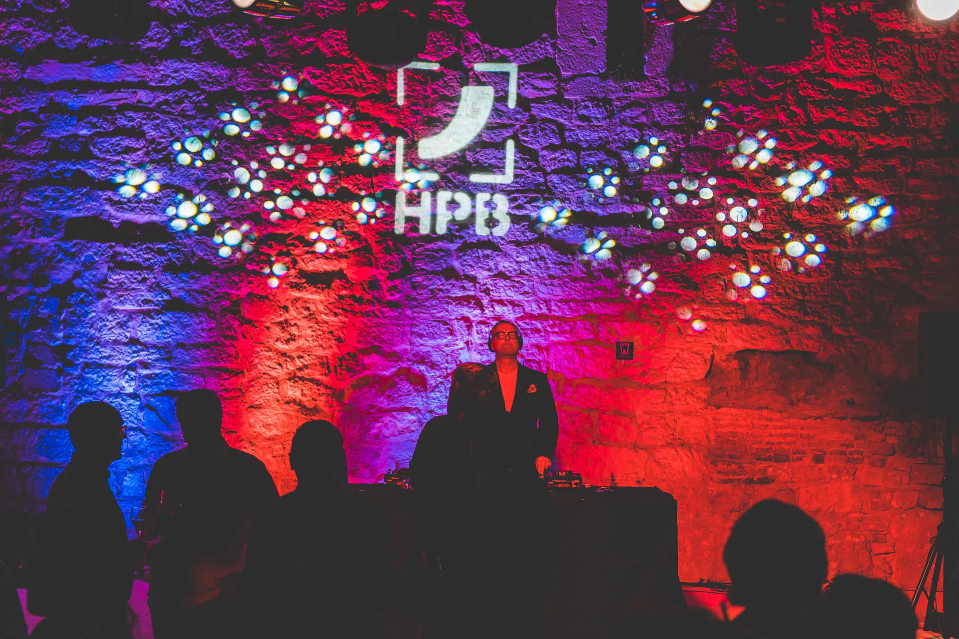 Corporate logo projected on fortress wall with DJ silhouette — Cosmic Production branded event