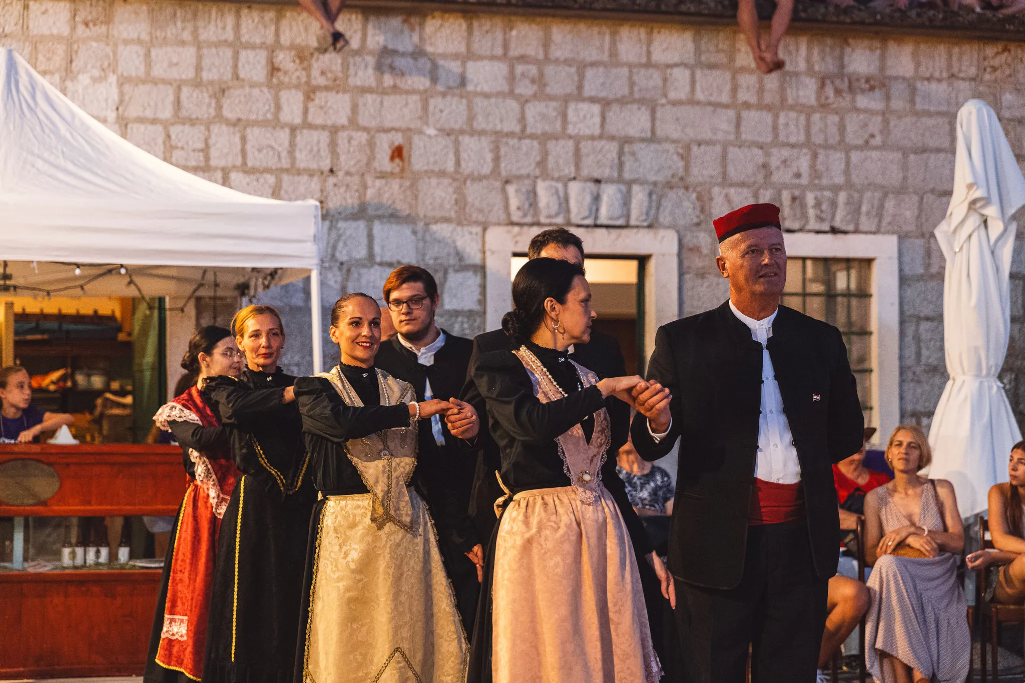 Croatian folk dancers in traditional costumes performing at a Hvar festival with live music coordination