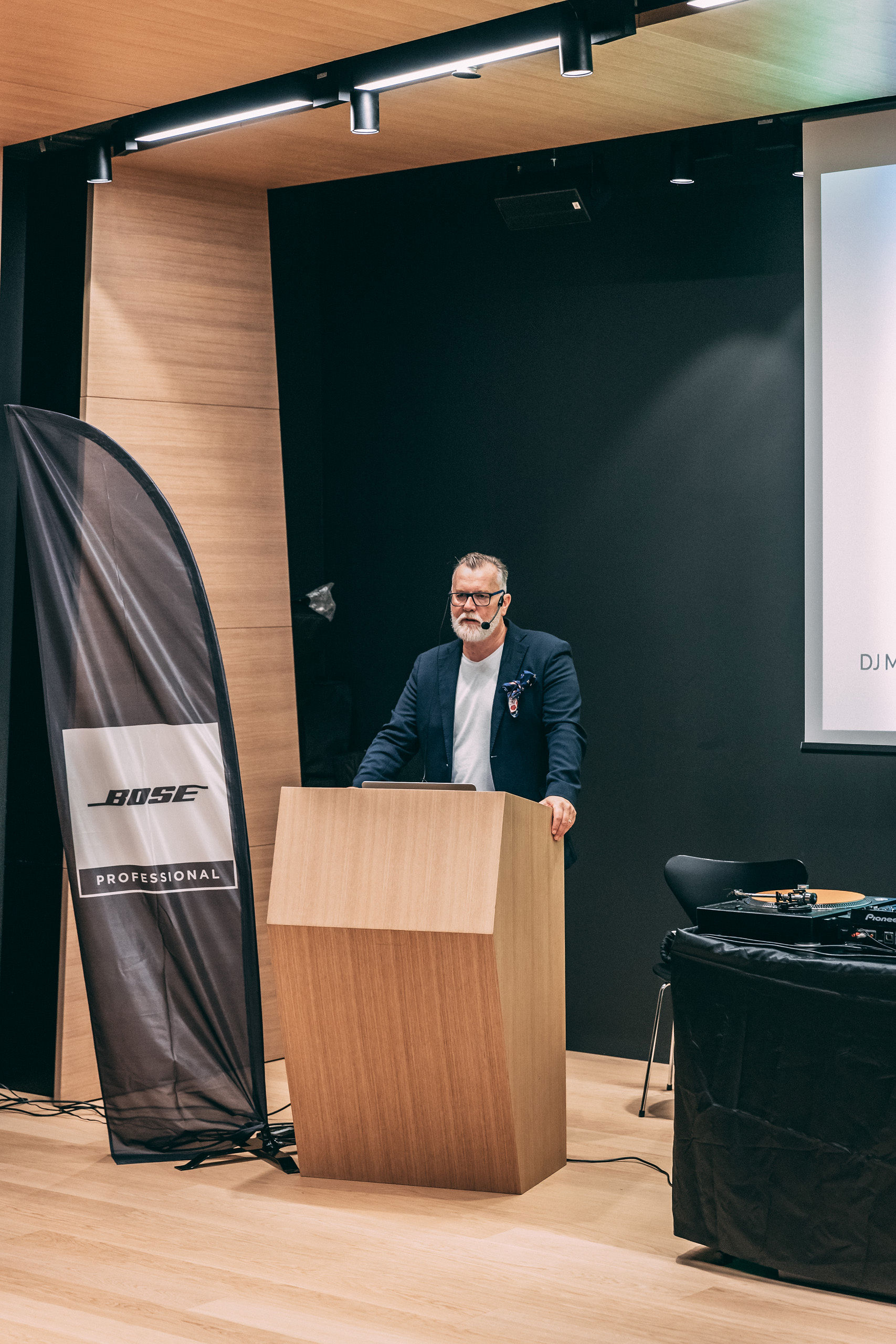 Matthew Bee presenting at Bose Professional branded DJ Masterclass with headset microphone and Bose banner
