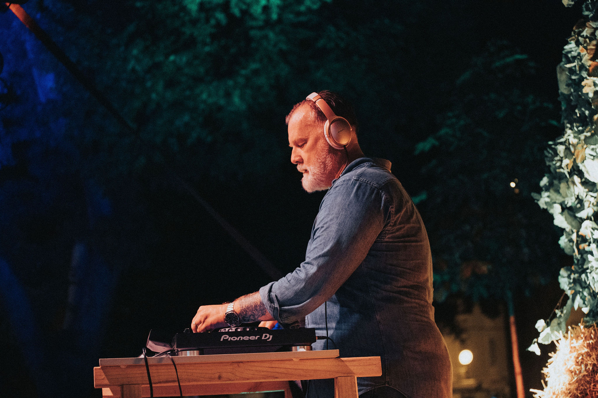 Cinematic side profile of DJ performing at night with copper headphones
