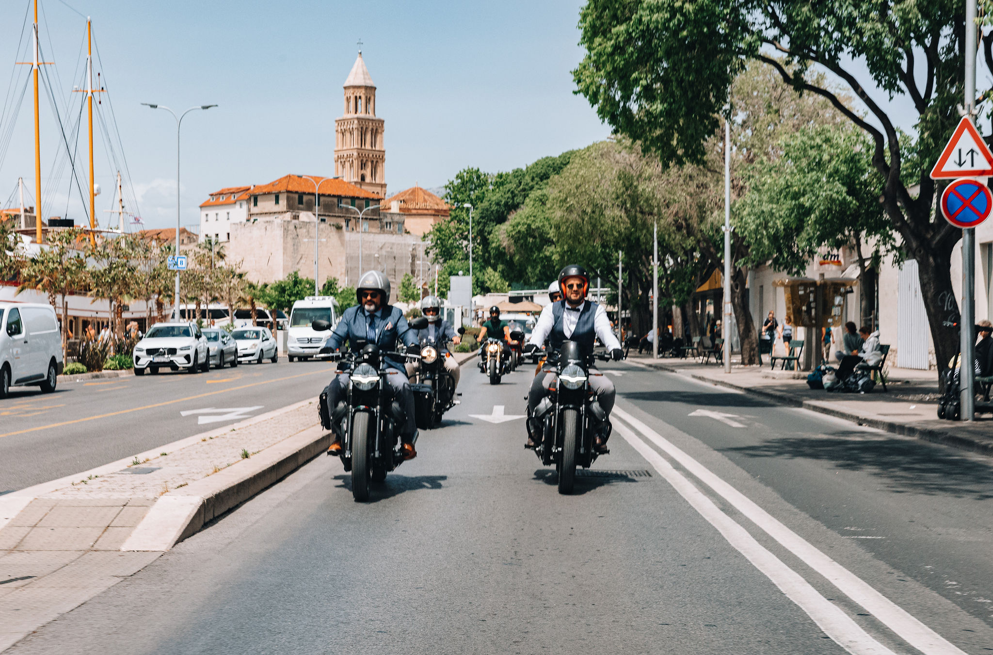 Three motorcycle riders at Gentleman's Ride with Diocletian's Palace bell tower behind in Split