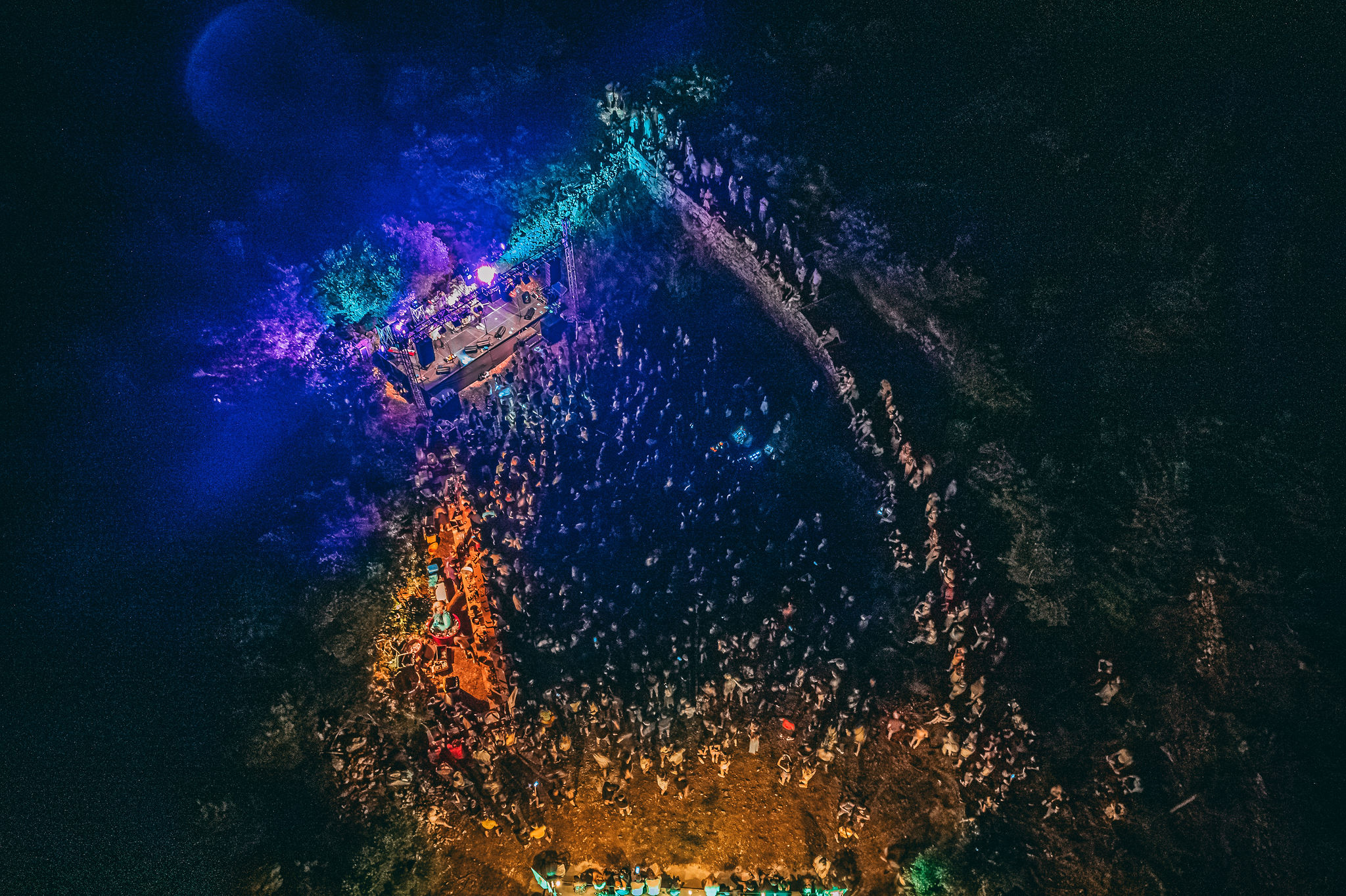 Aerial night view of outdoor concert at Lavender Festival in natural amphitheater on Hvar with food stalls and olive trees