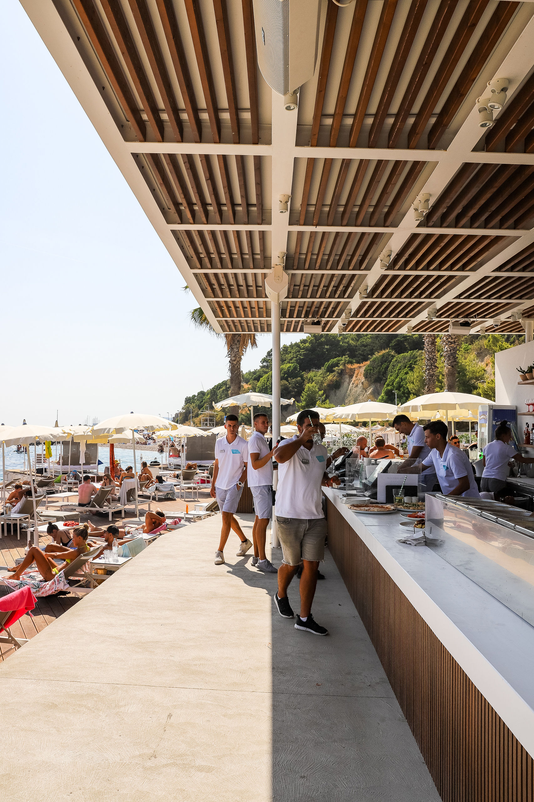 Mistral Beach Club bar area with wooden pergola and guests at Radisson Blu Split beach