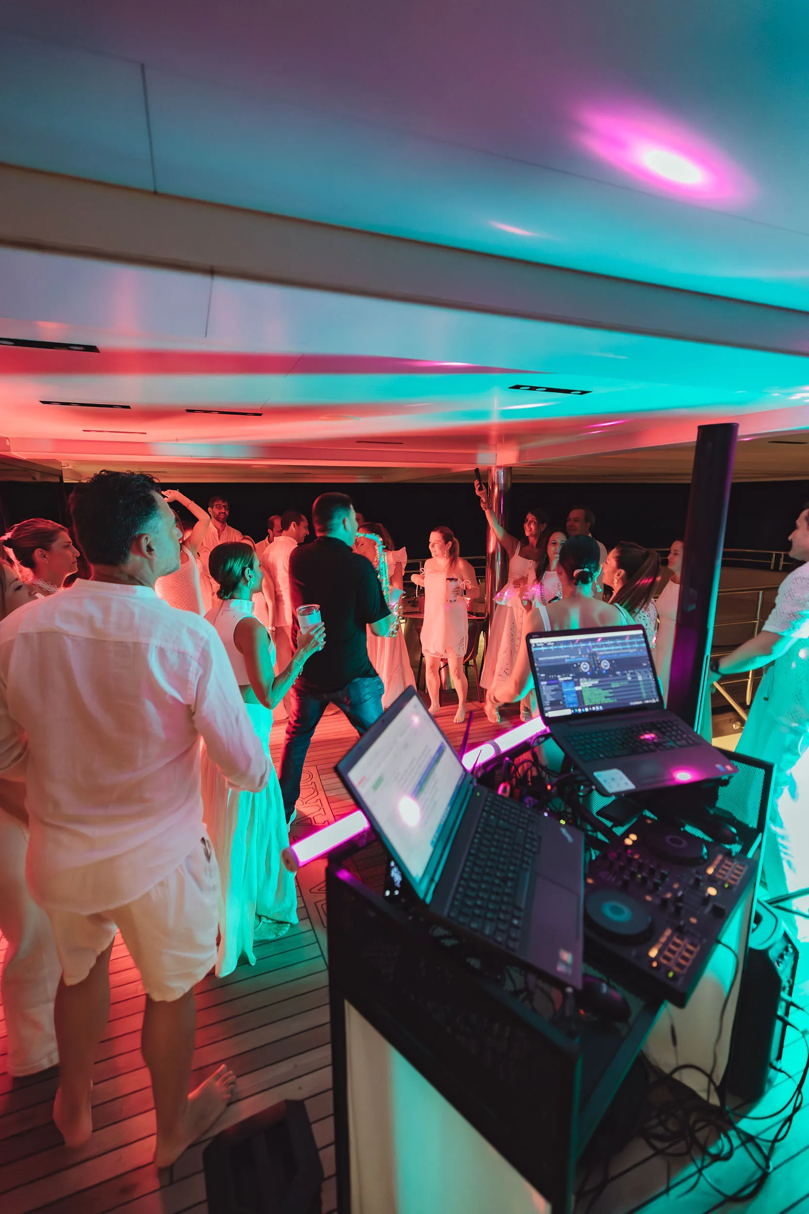 Pioneer CDJ setup on a yacht dance floor with pink and teal lighting — Cosmic Production yacht party production