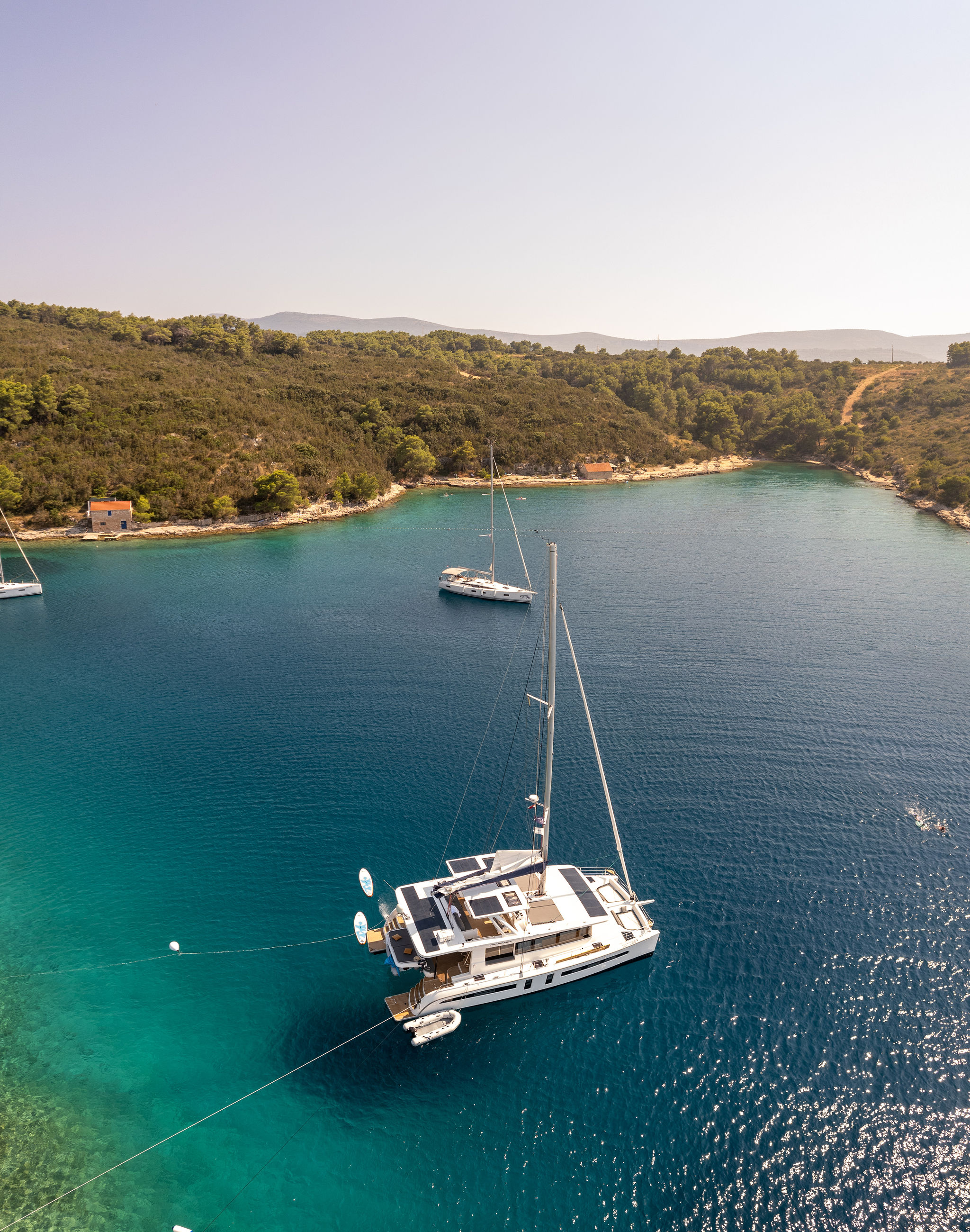 Aerial view of an Adriatic cove near Hvar, with a catamaran moored in turquoise water