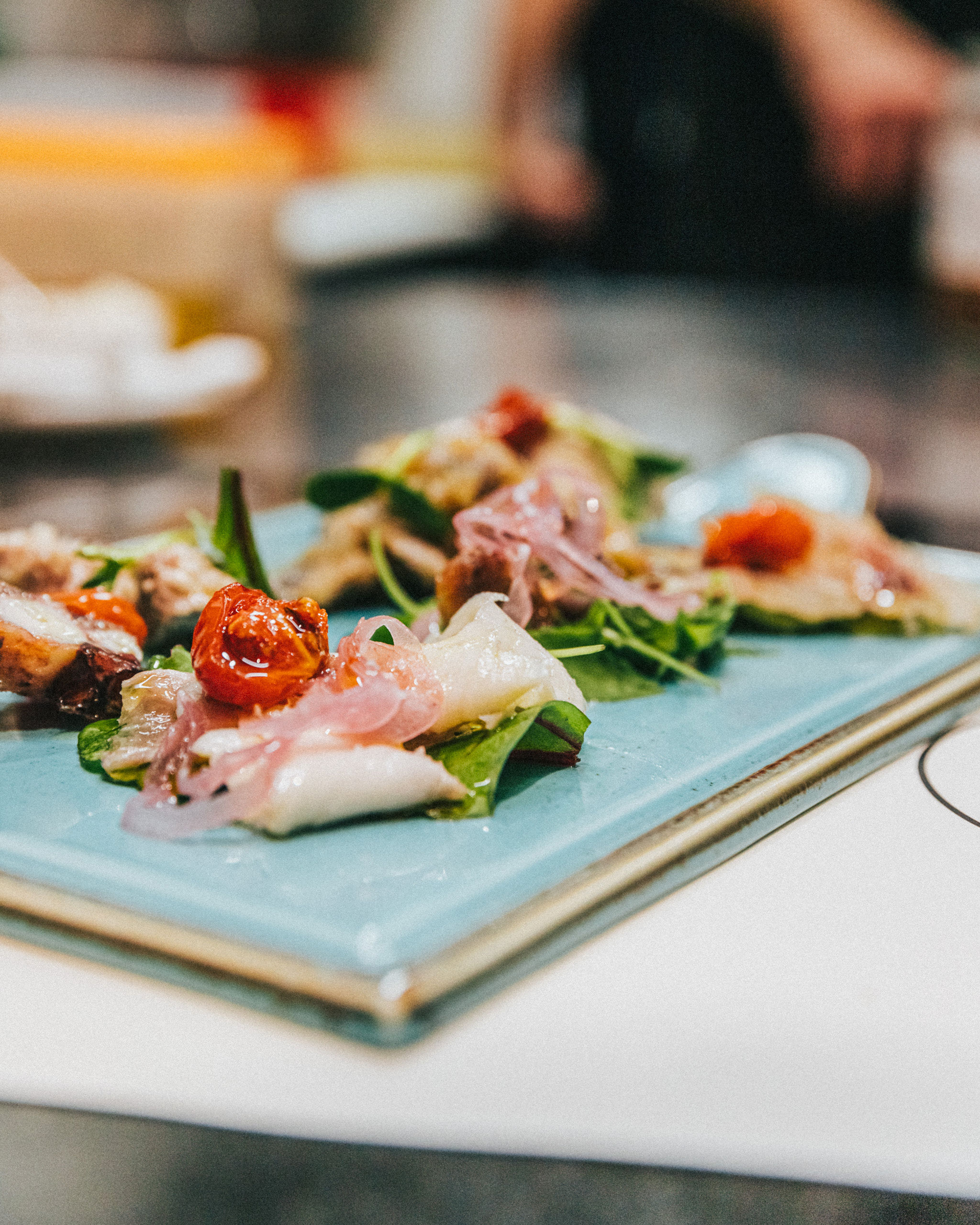 Professional food photography of plated Mediterranean dish on blue ceramic plate at Restoran Struja